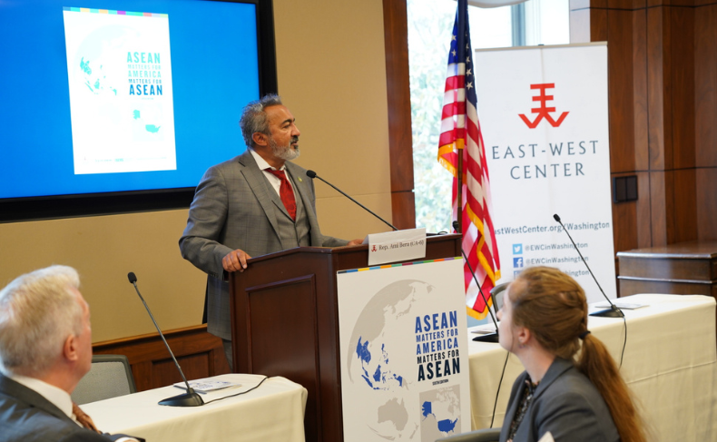 A man in a suit (Representative Ami Bera) speaks at a podium in front of an audience.
