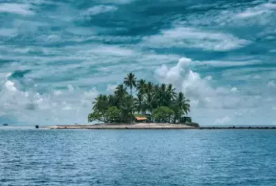 Island in a wide ocean under a blue sky