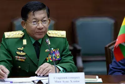 Myanmay coup leader Senior Gen. Min Aung Hlaing seen sitting at desk with a smal flag in 2017.