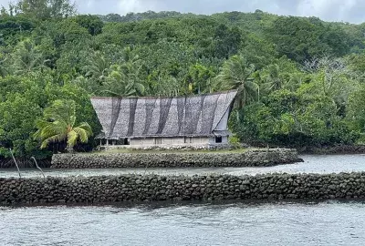 A thatched-roof men's house in Yap sitting on stonework above the waterline