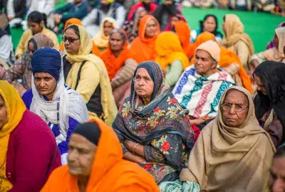 Indian women farmers listen to speaker as they sit in a protest against the new farm laws