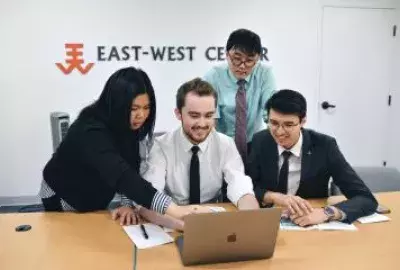 4 young people surround a laptop at a desk