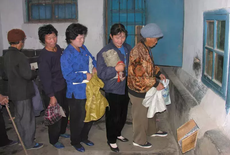  North Korean women queue to receive corn at a public distribution center. Photo by Gerald Bourke/WFP via Getty Images