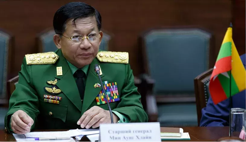 Myanmay coup leader Senior Gen. Min Aung Hlaing seen sitting at desk with a smal flag in 2017.