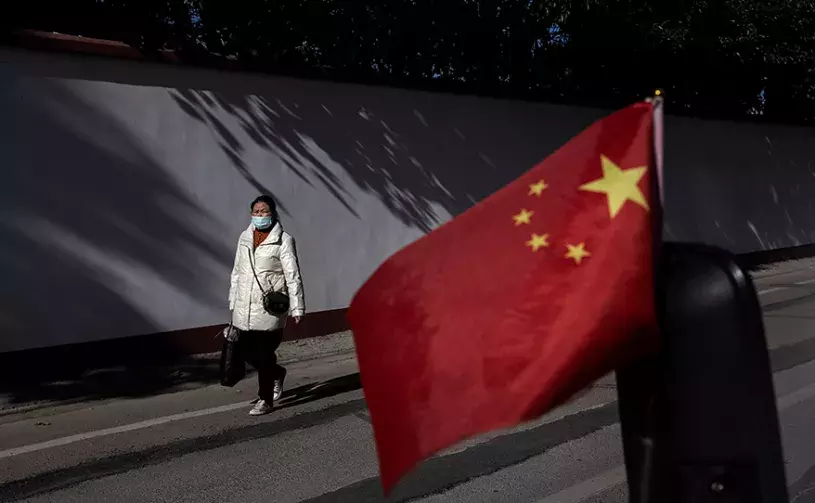 esidents wear masks while walking in street as the national flag waves on November 30, 2021 in Wuhan, China. Life for many of the residents in Wuhan is returning to normal a year and a half after the city imposed strict lockdowns to reduce the spread of COVID-19. (Photo by Getty Images)