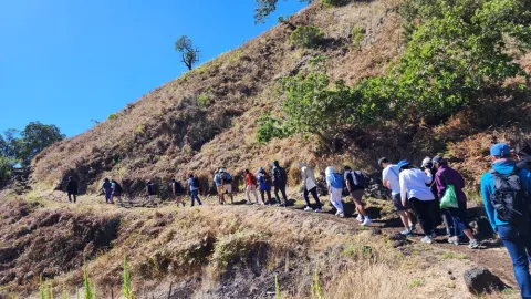 Participants of the 2023 Asia Pacific Leadership Program hiking Kipuka Pu'u Huluhulu during field study on Hawaii island.